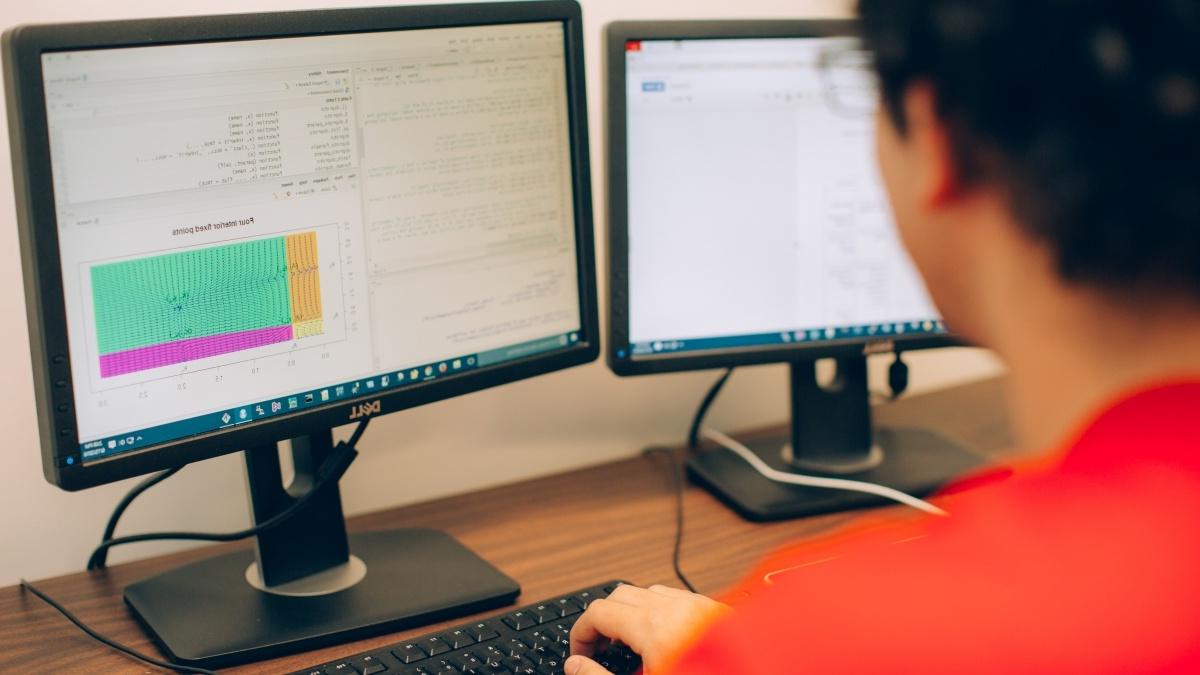 Student looks at code on a computer. 